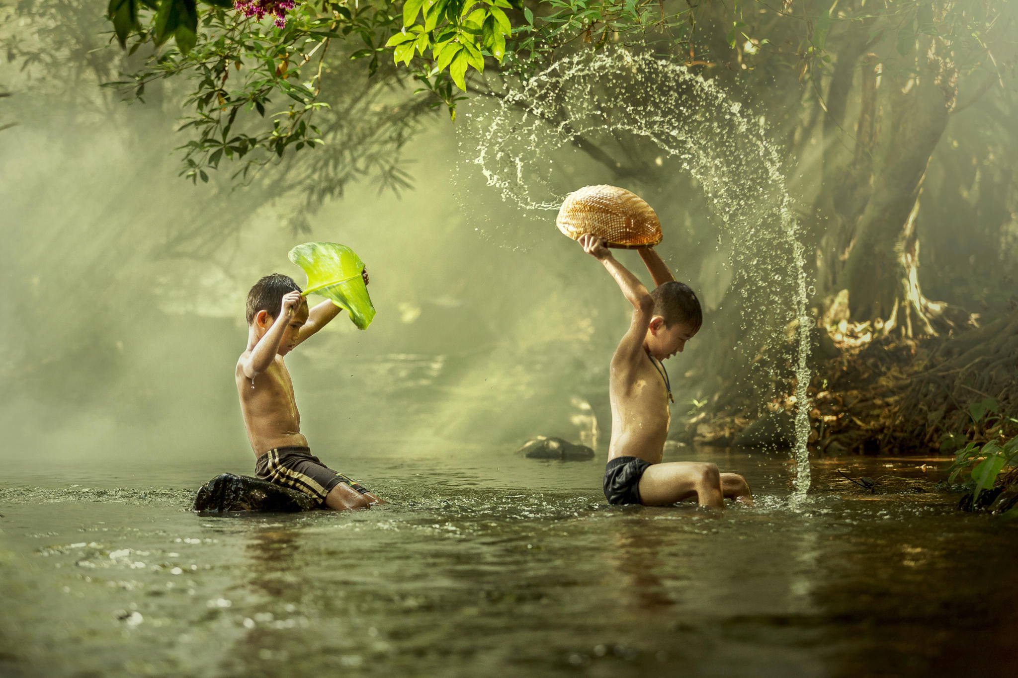 Thai boys splashing with his friend in a river.